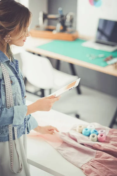 Modedesignerin arbeitet im Atelier mit iPad an ihren Entwürfen — Stockfoto