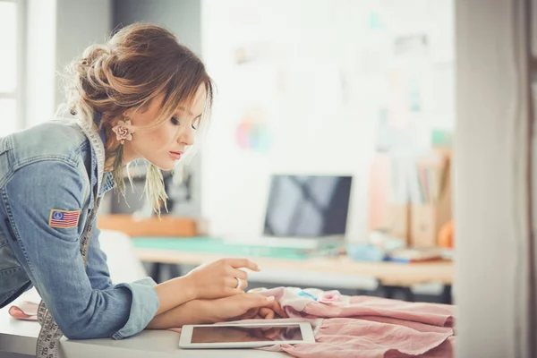 Modedesignerin arbeitet im Atelier mit iPad an ihren Entwürfen — Stockfoto