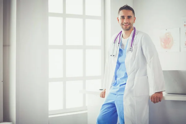 Junge und selbstbewusste männliche Ärztin steht in Arztpraxis. — Stockfoto