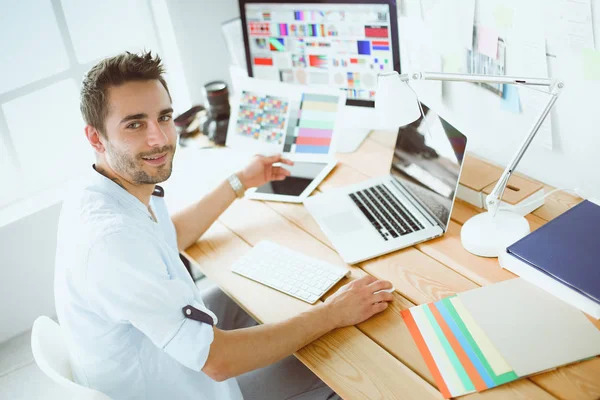 Porträt eines jungen Designers, der im Grafikstudio vor Laptop und Computer sitzt, während er online arbeitet. — Stockfoto