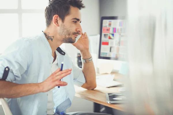 Porträt eines jungen Designers, der im Grafikstudio vor Laptop und Computer sitzt, während er online arbeitet. — Stockfoto