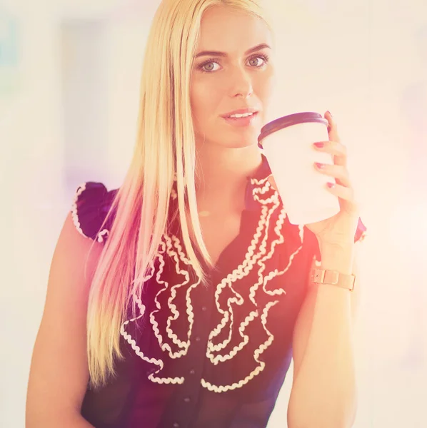 Podnikatelka, držící šálek kávy stojí v úřadu — Stock fotografie