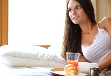 bir bardak süt ile yatakta oturan genç kadın