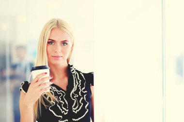 Ofiste bir fincan kahve ayakta tutan işkadını .