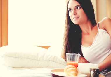 bir bardak süt ile yatakta oturan genç kadın