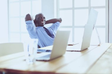 Kulaklıklı Afro-Amerikan işadamı laptopuyla çalışıyor.