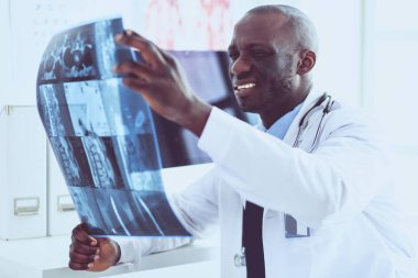 Genç Afrikalı doktor portresi hastaların röntgenlerini tutuyor.