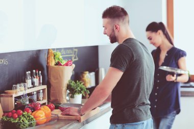 Bir çift evdeki mutfaklarında birlikte yemek pişiriyor.