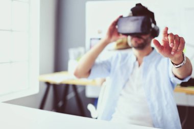 Genç erkek yazılım programcısı ofiste üç boyutlu sanal gerçeklik gözlükleriyle yeni bir uygulama test ediyor..