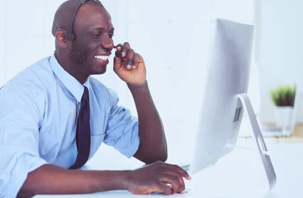 Afrikansk amerikansk affärsman på headset arbetar på sin bärbara dator — Stockfoto
