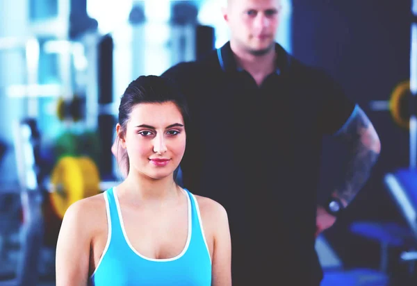 Beautiful woman at the gym exercising with her trainer. Beautiful woman. Gym