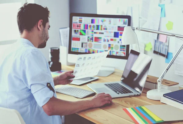 Porträt eines jungen Designers, der im Grafikstudio vor Laptop und Computer sitzt, während er online arbeitet. — Stockfoto