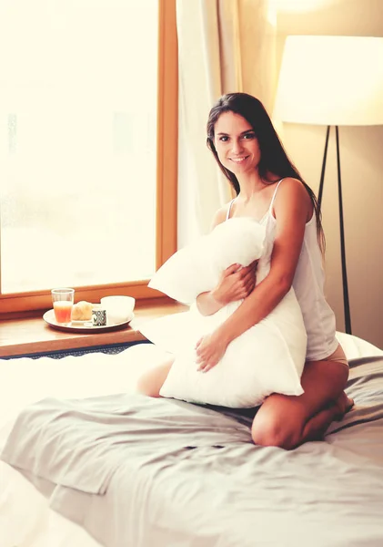 Junge Frau sitzt mit einer Tasse Milch im Bett — Stockfoto