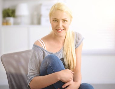 Genç ve güzel bir kadın odasında kanepede oturuyor.