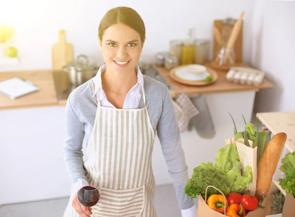 Femme avec des sacs à provisions dans la cuisine à la maison, debout près du bureau — Photo