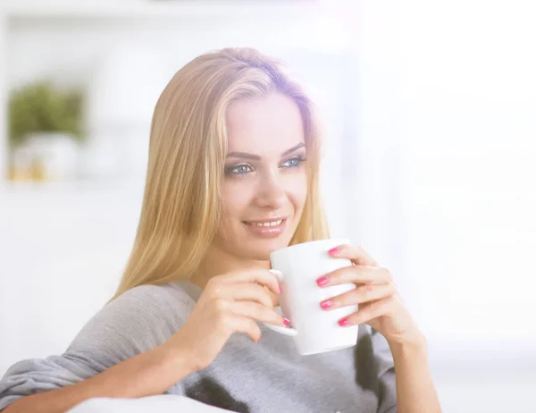 Jovem mulher bonita com uma xícara no sofá em casa — Fotografia de Stock
