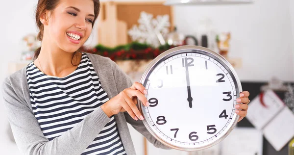 Happy young woman showing clock in christmas decorated kitchen — Stock Photo, Image