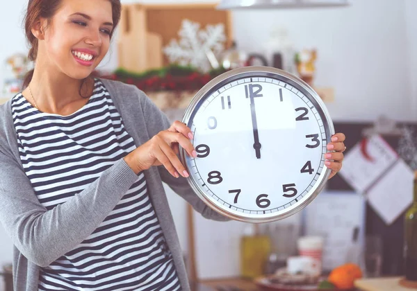 Joyeux jeune femme montrant horloge à Noël cuisine décorée — Photo