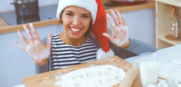 Lykkelig ung kvinde smilende glad for at have det sjovt med juleforberedelser iført Santa hat - Stock-foto