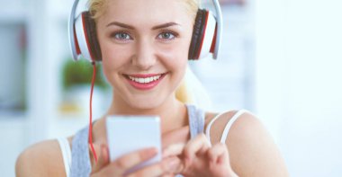 Evdeki genç ve güzel kadın kanepede oturup müzik dinliyor.