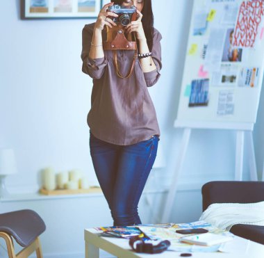 Genç bir kadın film izliyor, pencerenin yanında duruyor.