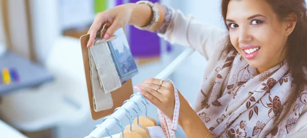 Schöne junge Stylistin in der Nähe von Gestell mit Kleiderbügeln — Stockfoto