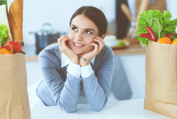 Portret van een lachende vrouw die in haar keuken zit te koken — Stockfoto