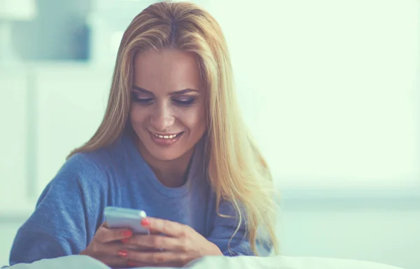 Mujer bonita en su sala de estar acostada en el sofá enviando un mensaje — Foto de Stock