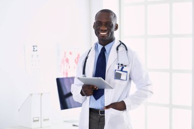 Tablet bilgisayarlı siyahi bir doktor hastanede bekliyor.