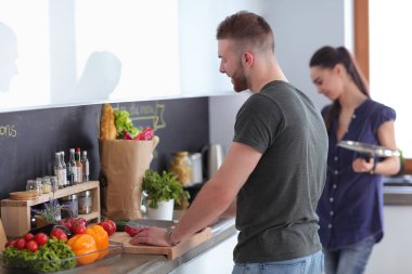 Bir çift evdeki mutfaklarında birlikte yemek pişiriyor.