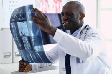Genç Afrikalı doktor portresi hastaların röntgenlerini tutuyor.