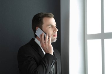 Modern ofiste cep telefonuyla konuşan yakışıklı iş adamı..