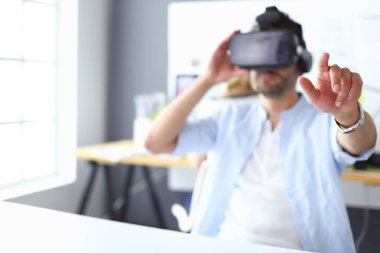 Genç erkek yazılım programcısı ofiste üç boyutlu sanal gerçeklik gözlükleriyle yeni bir uygulama test ediyor..