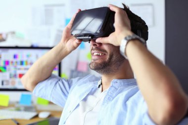 Genç erkek yazılım programcısı ofiste üç boyutlu sanal gerçeklik gözlükleriyle yeni bir uygulama test ediyor..