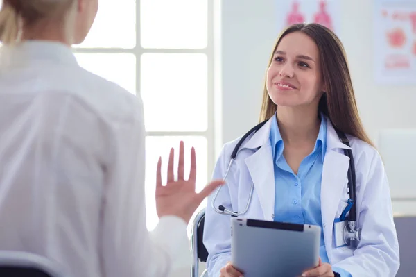 Médico e paciente discutindo algo enquanto se senta na mesa. Conceito de medicina e cuidados de saúde — Fotografia de Stock