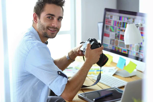 Retrato del joven diseñador sentado en el estudio gráfico frente a la computadora portátil y el ordenador mientras trabaja en línea. — Foto de Stock