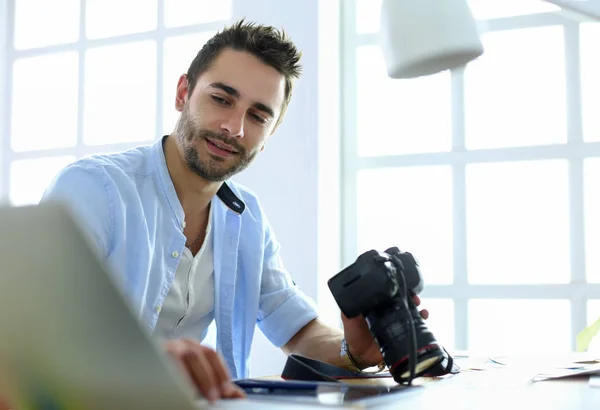 Portrét mladého návrháře sedícího v grafickém studiu před notebookem a počítačem při práci online. — Stock fotografie
