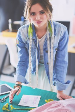 Moda tasarımcısı kadın stüdyoda tasarımları üzerinde çalışıyor.