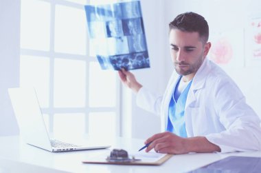 Yakışıklı doktor genç bayan hastasıyla konuşuyor ve ofisinde otururken notlar alıyor..
