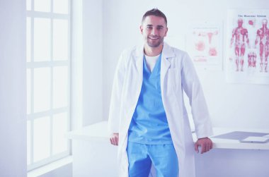 Genç ve kendinden emin erkek doktor portresi tıp ofisinde duruyor..