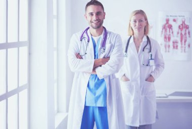 Yakışıklı doktor genç bayan doktorla konuşuyor ve ofisinde otururken notlar alıyor..