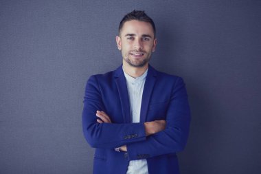 Gri arka planda yalnız oturan genç iş adamı.