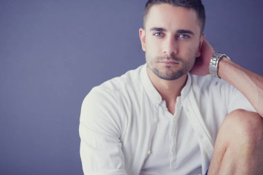 Gri arka planda yalnız oturan genç iş adamı.