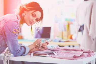 Moda tasarımcısı kadın stüdyoda tasarımları üzerinde çalışıyor.