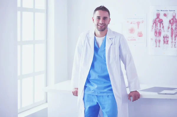 Młody i pewny siebie mężczyzna lekarz portret stojący w gabinecie medycznym. — Zdjęcie stockowe