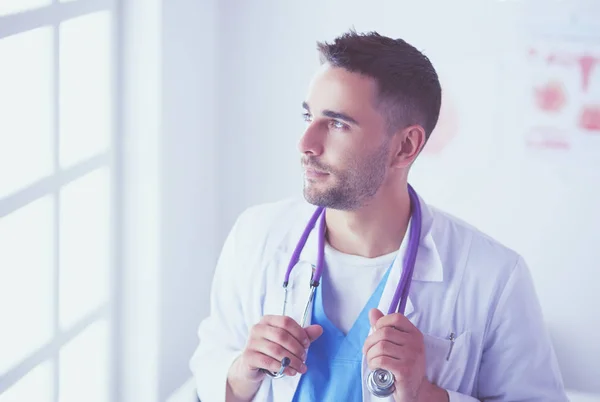 Ritratto di giovane e fiducioso medico maschio in piedi nello studio medico. — Foto Stock