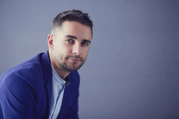 Joven empresario sentado aislado sobre fondo gris. —  Fotos de Stock