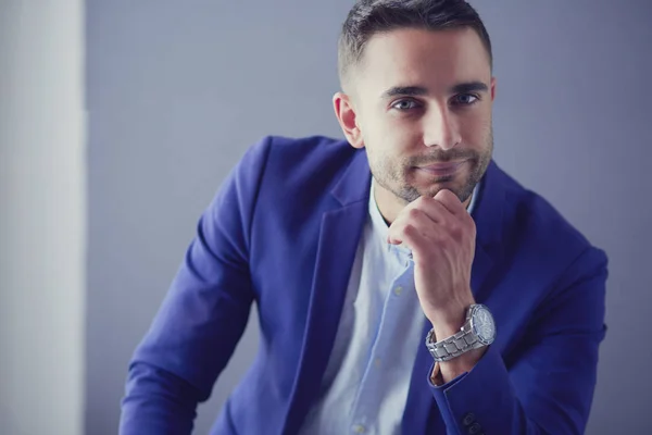 Joven empresario sentado aislado sobre fondo gris. — Foto de Stock