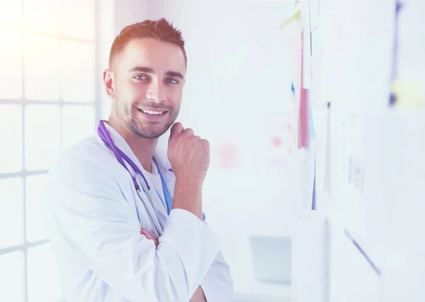 Retrato médico masculino joven y confiado de pie en el consultorio médico. — Foto de Stock