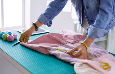 Moda tasarımcısı kadın stüdyoda tasarımları üzerinde çalışıyor.